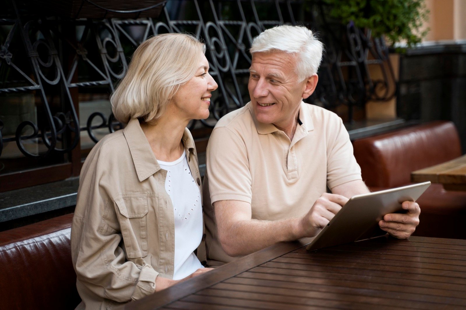 Seniorpar sidder i byen med tablet og planlægger et lokalt møde